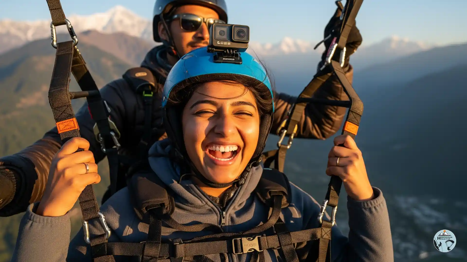 A first-time flyer laughing during a tandem paragliding flight over Solang Valley with the pilot in the background
